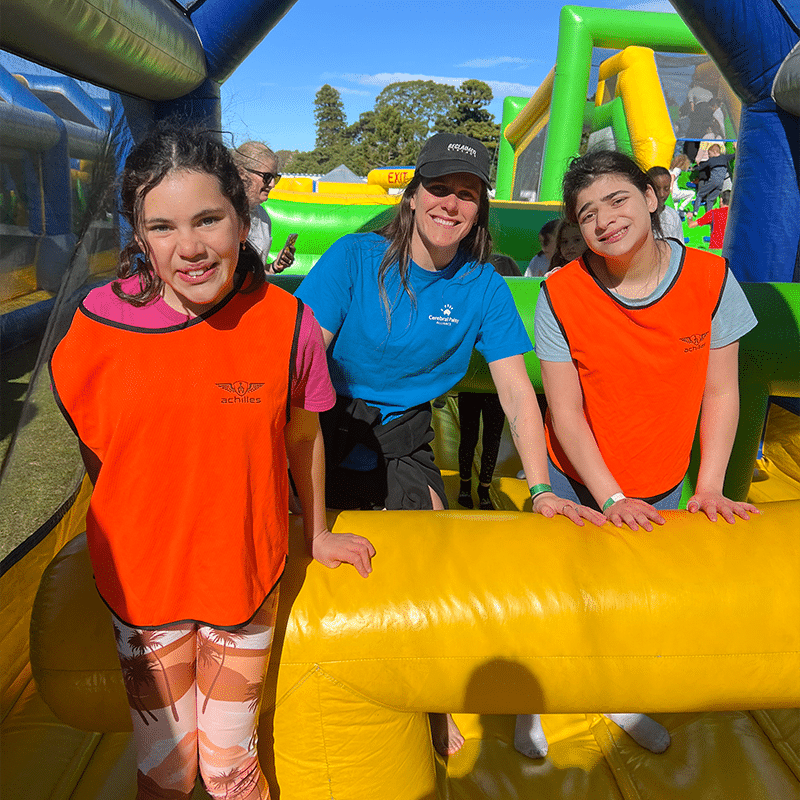 Three girls smiling for the camera standing in an inflatable obstacle course